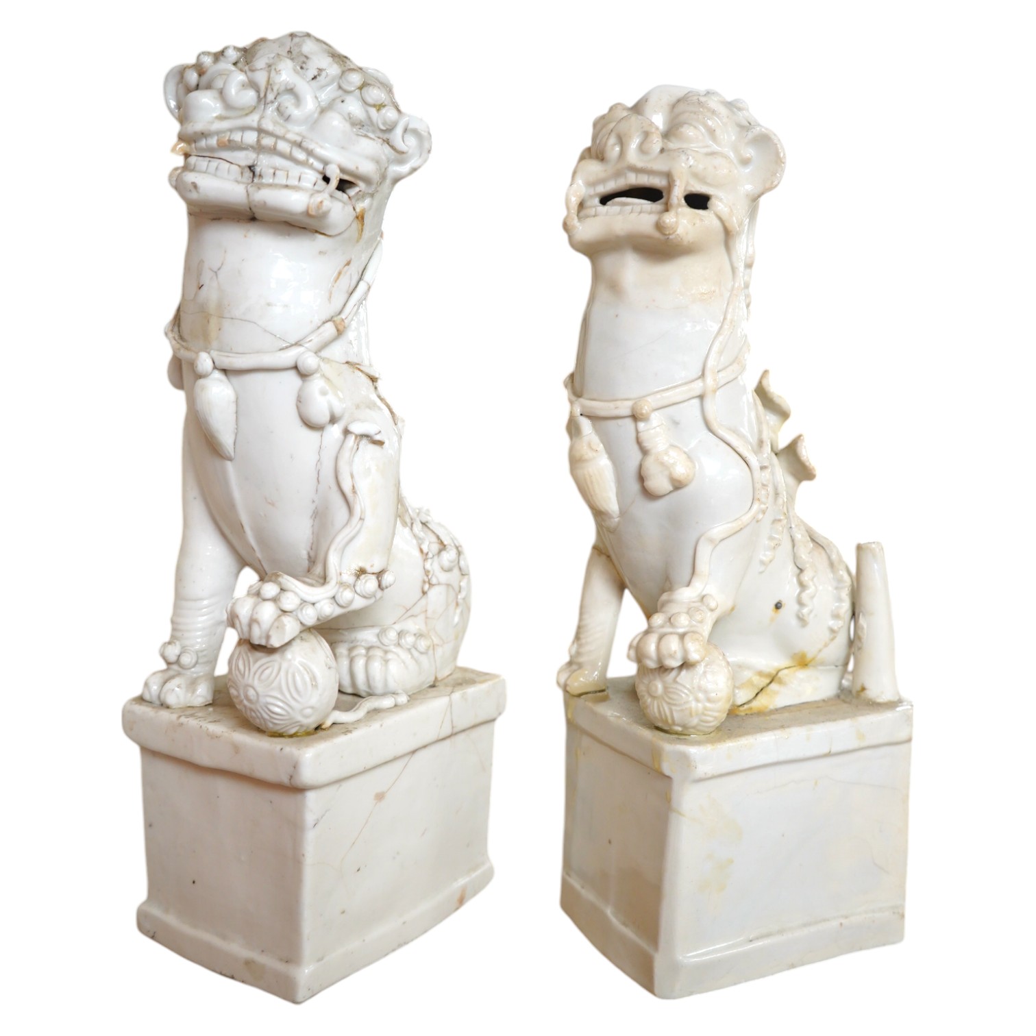 Two large Chinese Dehua blanc de chine Buddhist lion joss-stick holders, Kangxi period, each seated, one paw raised on a ball, on rectangular pedestal basis, 35cm high, Condition - extensive cracks or repairs